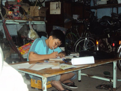 Thành Kỳ học bài ngay tại tiệm sửa xe - Ảnh: N.Hạnh